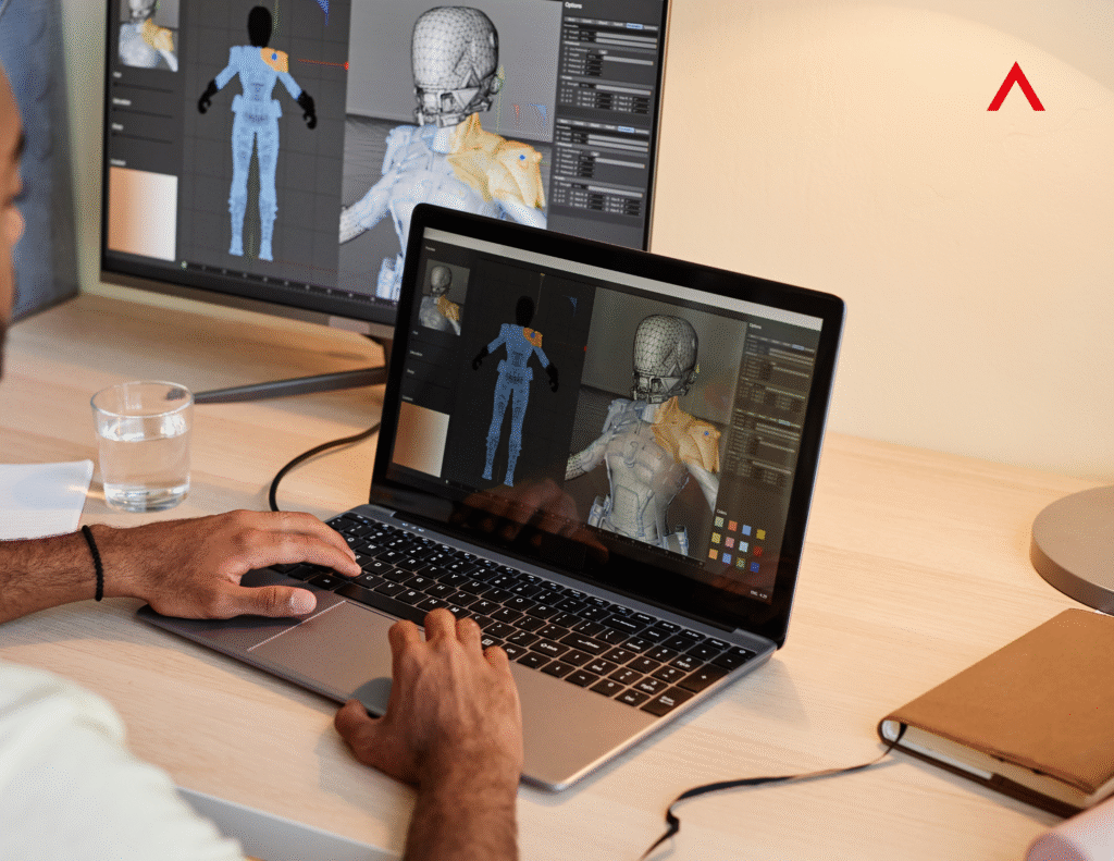 Designer working on 3D motion graphics character model on a laptop and monitor in a creative workspace.